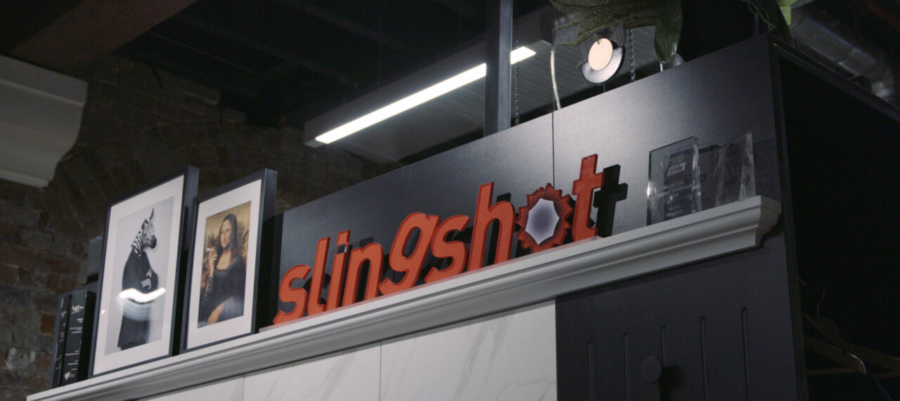 A mantlepiece with framed pictures and a sign saying Slingshot